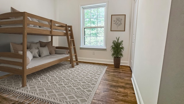 bedroom with multiple windows, baseboards, and wood finished floors
