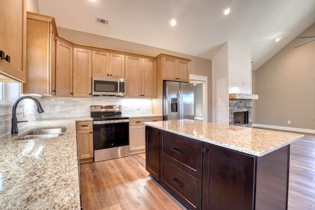 kitchen with light stone counters, sink, lofted ceiling, and appliances with stainless steel finishes