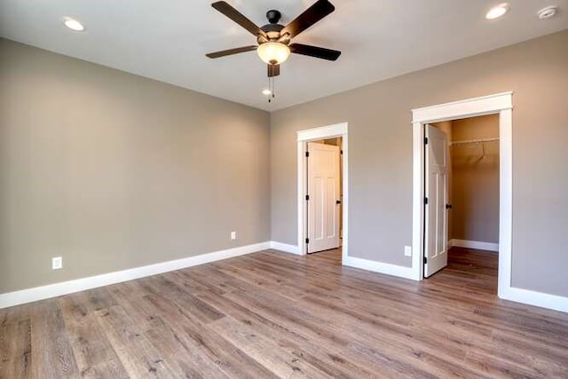 unfurnished bedroom featuring light hardwood / wood-style floors, a spacious closet, and ceiling fan