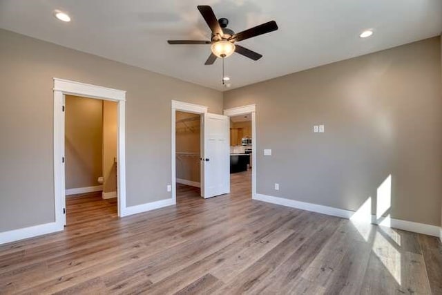 unfurnished bedroom featuring a spacious closet, light hardwood / wood-style flooring, and ceiling fan