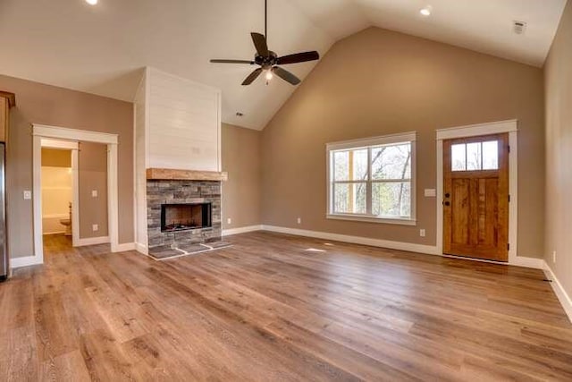 unfurnished living room featuring ceiling fan, light wood-type flooring, a fireplace, and high vaulted ceiling