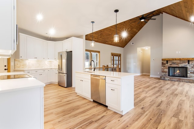 kitchen featuring white cabinetry, sink, stainless steel appliances, a stone fireplace, and high vaulted ceiling