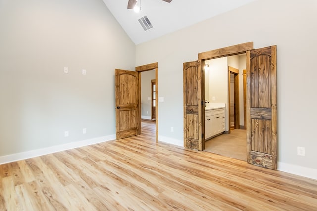 unfurnished bedroom with ensuite bath, ceiling fan, high vaulted ceiling, and light wood-type flooring