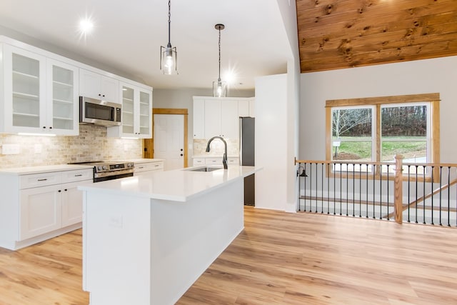 kitchen with pendant lighting, white cabinets, sink, an island with sink, and appliances with stainless steel finishes