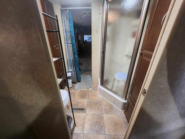 bathroom featuring stone tile flooring, a stall shower, and visible vents