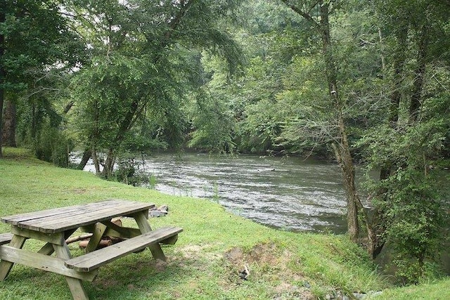 exterior space with a water view, a view of trees, and a lawn