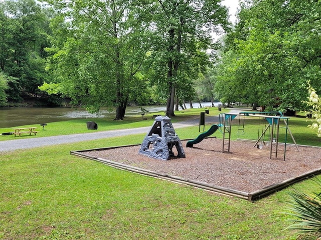 view of community featuring a playground, a yard, and a water view