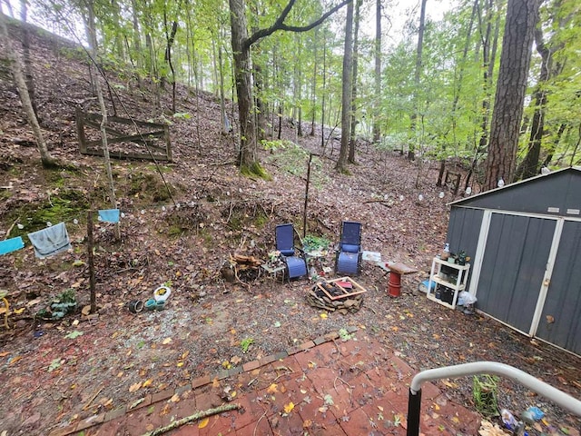view of yard with an outbuilding, a storage unit, and a forest view