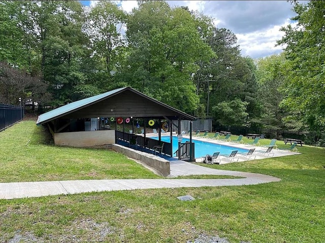 community pool with fence, a yard, and a patio area