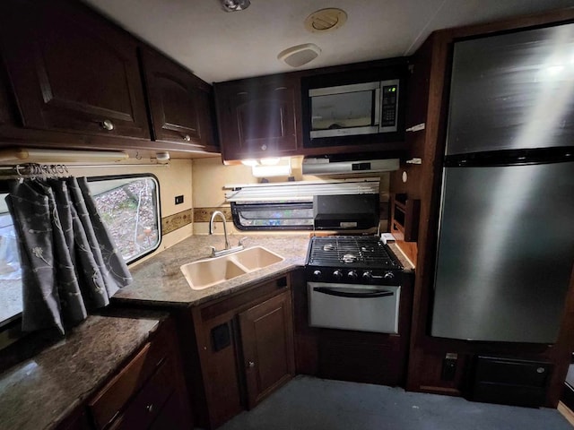 kitchen with light stone countertops, stainless steel appliances, dark brown cabinets, a sink, and exhaust hood