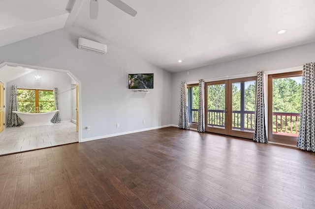 unfurnished living room with a healthy amount of sunlight, vaulted ceiling, wood-type flooring, and a wall mounted air conditioner