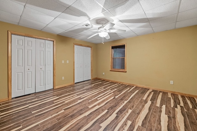 unfurnished bedroom with hardwood / wood-style floors, ceiling fan, and a drop ceiling