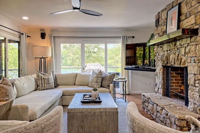 living room featuring a fireplace, a ceiling fan, baseboards, wood finished floors, and ornamental molding