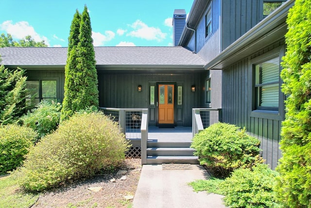 doorway to property featuring roof with shingles, board and batten siding, a chimney, and a porch