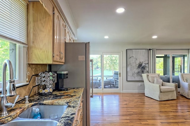 kitchen featuring a sink, stone countertops, wood finished floors, and a wealth of natural light