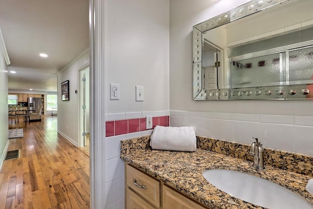 bathroom with vanity, crown molding, wood finished floors, recessed lighting, and a shower with shower door