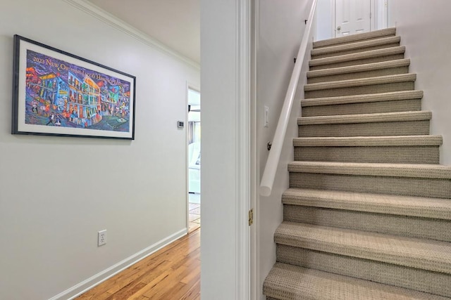 staircase with crown molding, baseboards, and wood finished floors