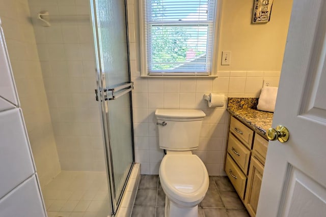 full bathroom featuring tile walls, a stall shower, vanity, tile patterned floors, and toilet