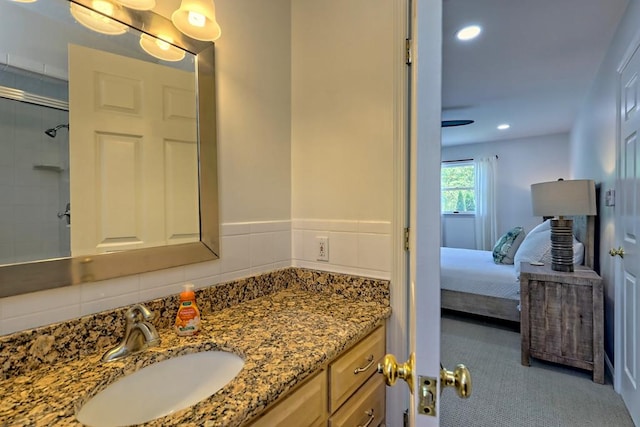 ensuite bathroom with connected bathroom, recessed lighting, tiled shower, and vanity