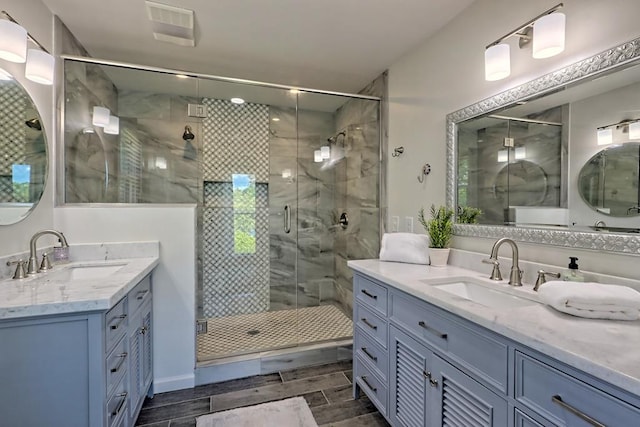full bath featuring a sink, two vanities, wood tiled floor, and a shower stall