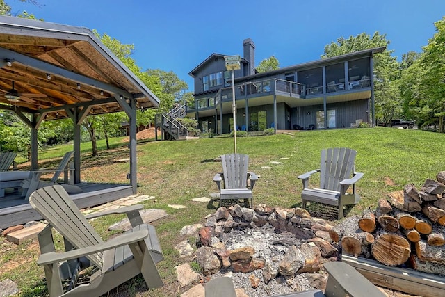 view of yard with a sunroom, a ceiling fan, stairs, and a deck