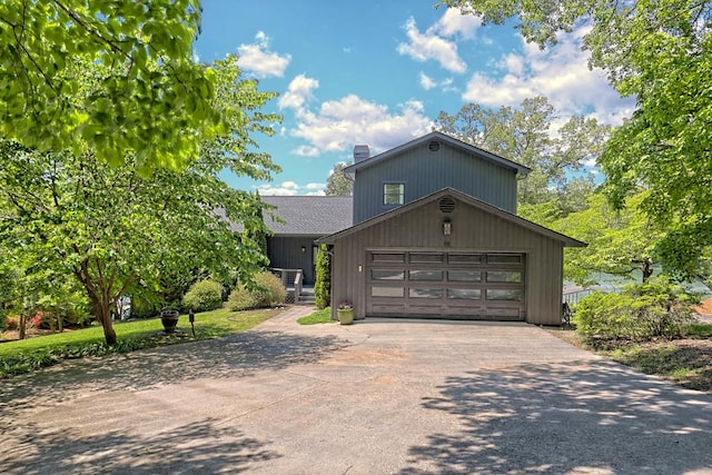 view of front facade with driveway, a chimney, and a garage