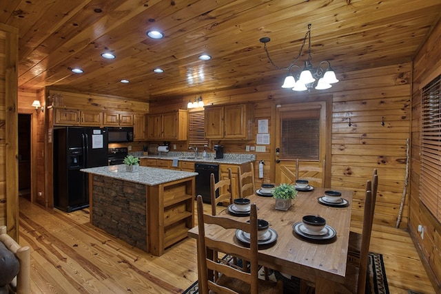 kitchen featuring a center island, black appliances, light hardwood / wood-style flooring, and wooden walls