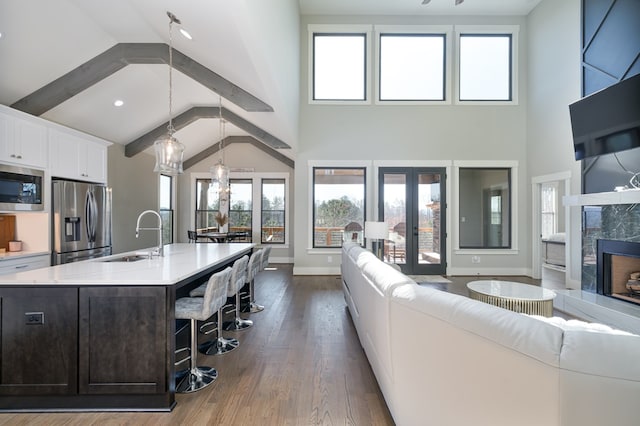 living room with a fireplace, high vaulted ceiling, dark hardwood / wood-style flooring, sink, and beam ceiling