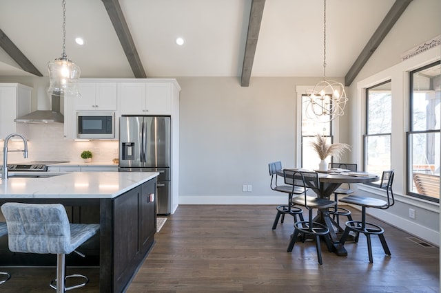 kitchen featuring hanging light fixtures, dark hardwood / wood-style flooring, appliances with stainless steel finishes, and vaulted ceiling with beams