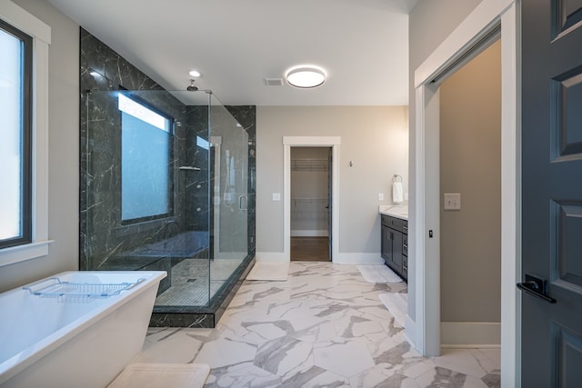 bathroom with marble finish floor, a stall shower, baseboards, a soaking tub, and vanity