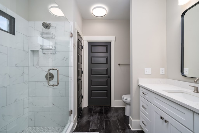 full bathroom featuring a stall shower, toilet, vanity, and baseboards