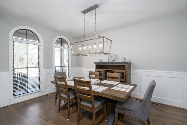 dining room featuring a wainscoted wall and dark wood-type flooring