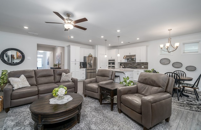 living room with ceiling fan with notable chandelier, light wood-type flooring, and crown molding