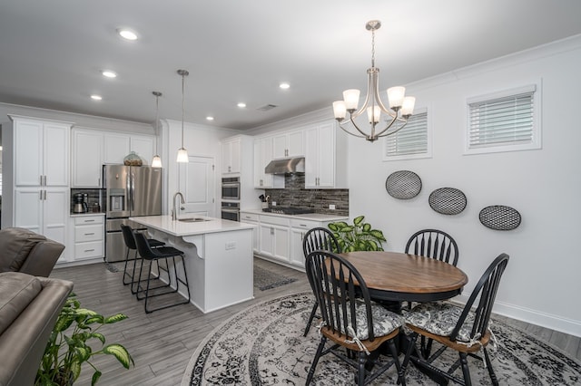 dining room featuring a chandelier, light hardwood / wood-style flooring, crown molding, and sink