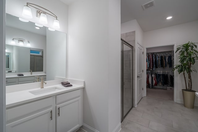 bathroom featuring tile patterned floors, a shower with door, and vanity