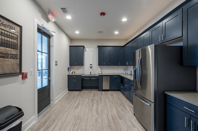 kitchen featuring decorative backsplash, sink, stainless steel appliances, and light hardwood / wood-style flooring