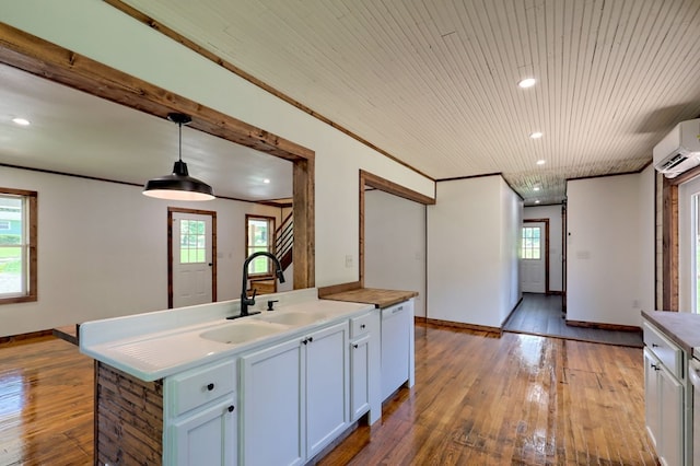 kitchen featuring hanging light fixtures, light hardwood / wood-style flooring, a wealth of natural light, and a kitchen island with sink