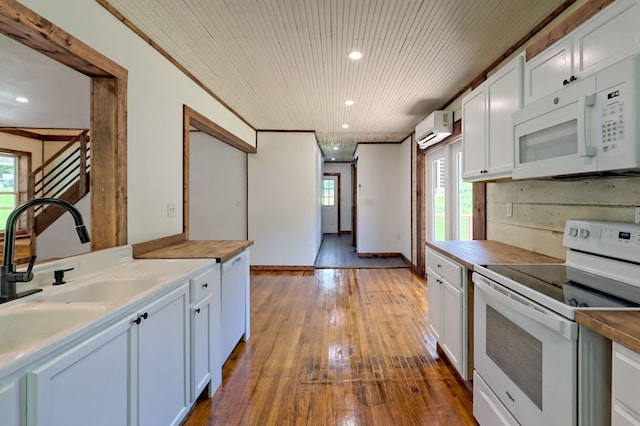 kitchen with white appliances, white cabinets, hardwood / wood-style flooring, a wall mounted air conditioner, and ornamental molding