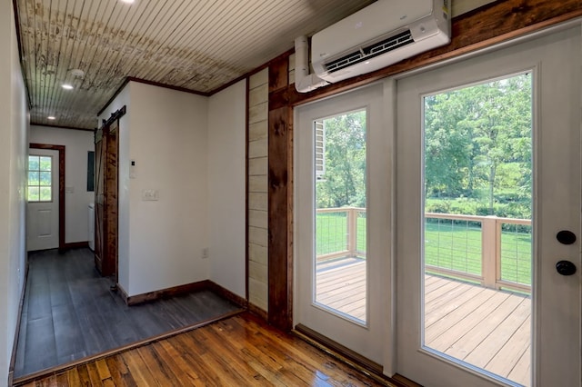 entryway with a wall unit AC, a barn door, a wealth of natural light, and hardwood / wood-style flooring