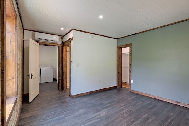 unfurnished bedroom with washer / dryer, an AC wall unit, hardwood / wood-style floors, and a barn door