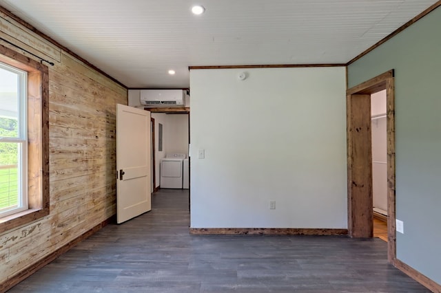 empty room with a wall unit AC, dark hardwood / wood-style flooring, wooden walls, and washing machine and clothes dryer