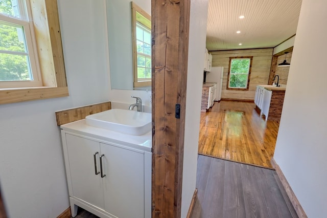 bathroom with vanity, wooden walls, and hardwood / wood-style floors