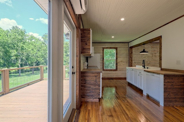 kitchen with wood walls, wood-type flooring, white dishwasher, and white cabinetry