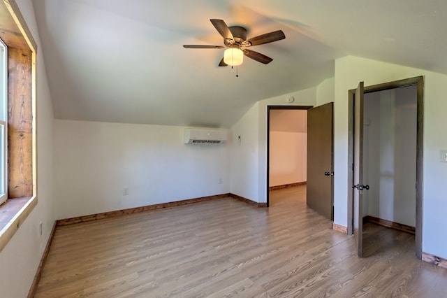 additional living space with an AC wall unit, ceiling fan, hardwood / wood-style flooring, and lofted ceiling