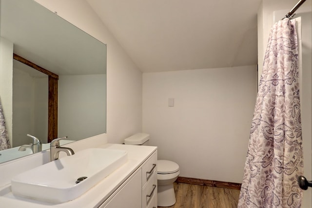 bathroom with vanity, hardwood / wood-style flooring, lofted ceiling, and toilet