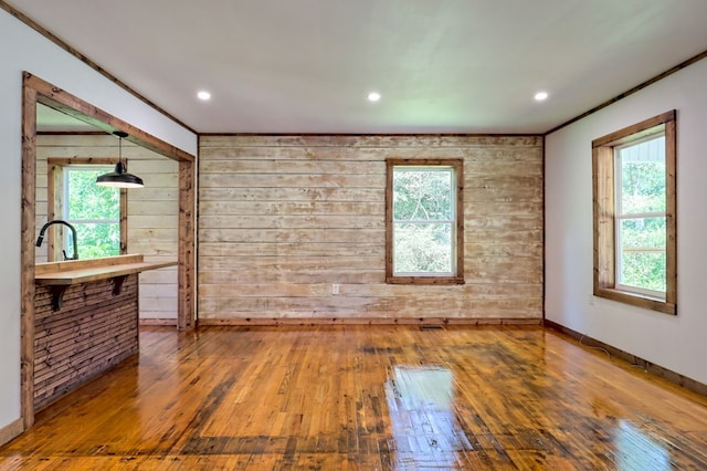 unfurnished room with wood walls, wood-type flooring, and plenty of natural light