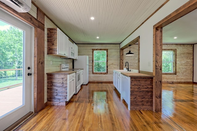 kitchen with wooden walls, white appliances, hardwood / wood-style floors, and white cabinets