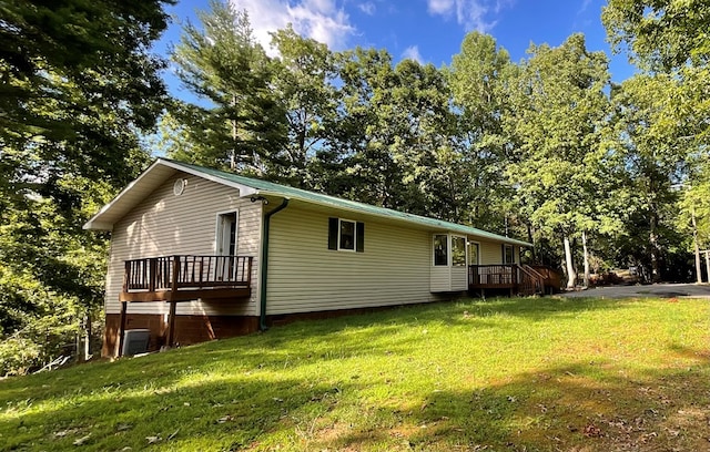 view of side of property with a deck, a yard, and central AC