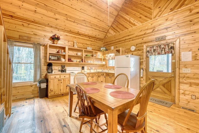 dining space with wooden walls, wood ceiling, high vaulted ceiling, and light wood-type flooring