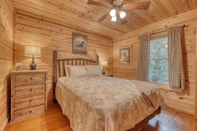 bedroom with wood walls, wooden ceiling, light wood-type flooring, and ceiling fan